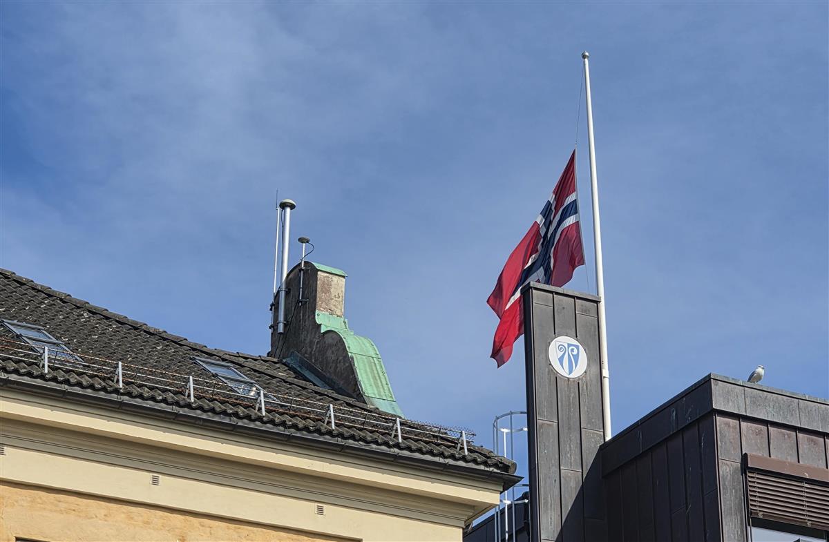 Det norske flagget vaier i vinden på halv stang på Tønsberg Rådhus - Klikk for stort bilde