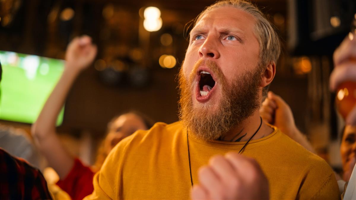 Mann på pub som roper mot det han ser på storskjermen - Klikk for stort bilde