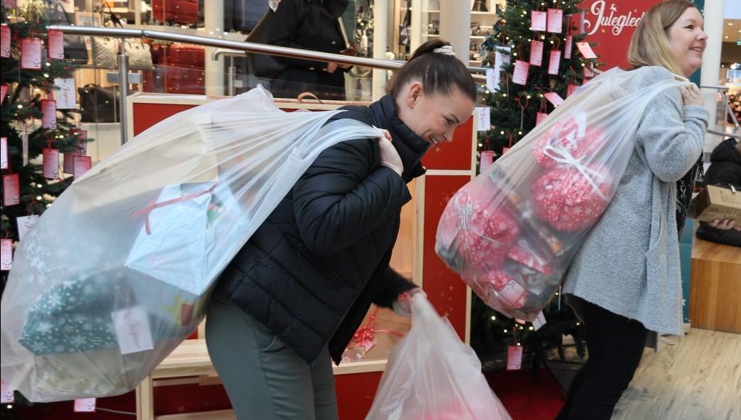 To damer med svære sekker på ryggen full av julegaver. - Klikk for stort bilde