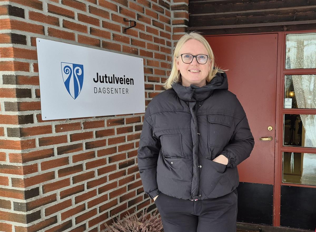 Bodil Bøe Bettum utenfor inngangen ved skilt med teksten Jutulveien dagsenter. - Klikk for stort bilde