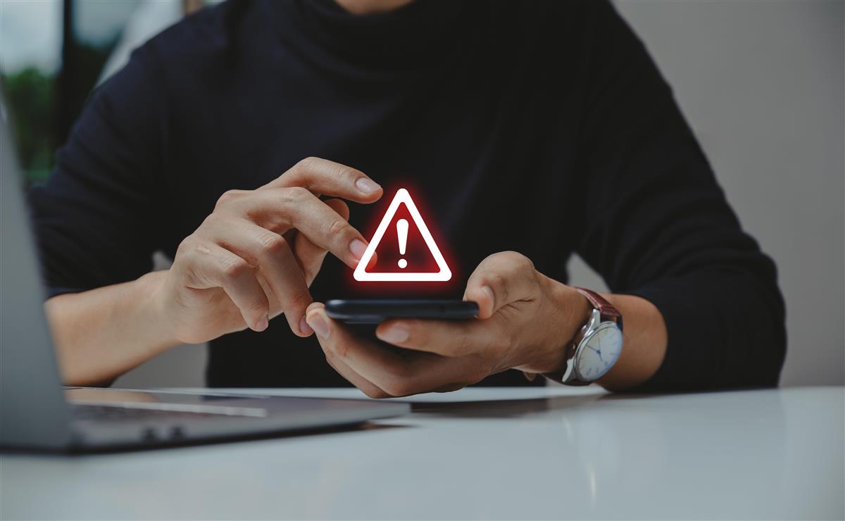 Bilde av mann med mobil og PC og en varselstrekant - Klikk for stort bilde