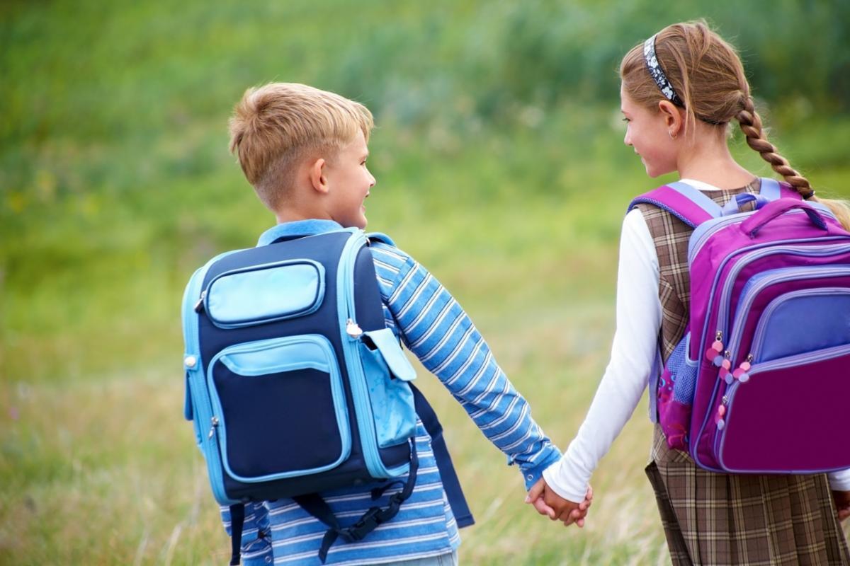 En gutt og ei jente som leier hverandre på vei til skolen - Klikk for stort bilde